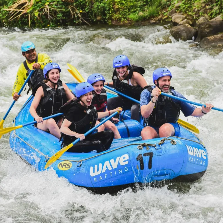 Family laughing and paddling through rapids during a whitewater rafting tour in Costa Rica