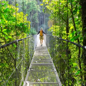 Traveler walking across a suspension bridge in the rainforest with Wave Costa Rica