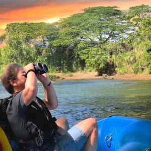 Traveler birdwatching from raft during WAVE’s Nature Safari Float Tour on the Peñas Blancas River