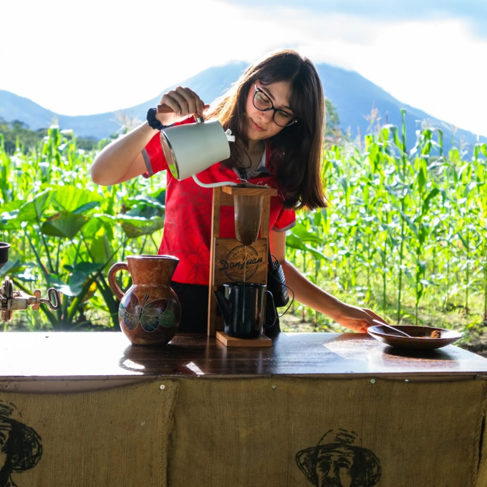 Woman preparing coffee and cacao with volcano in background
